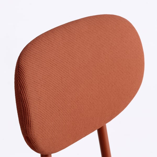 Rust-colored chair with a circular backrest and splayed wooden legs. The fabric is finely textured, giving a quality feel.