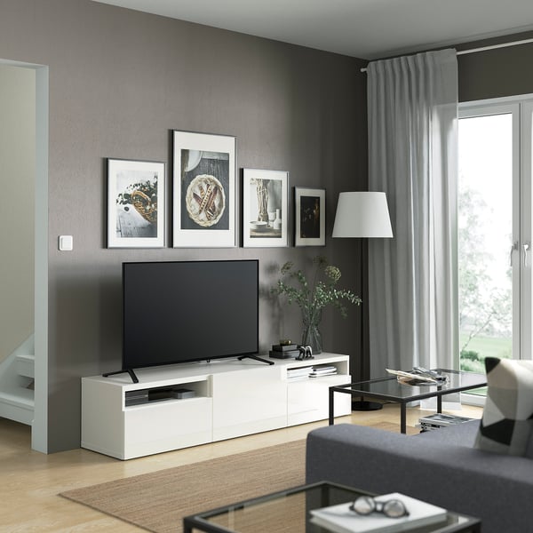 Modern living room with SELSVIKEN tv stand, tv, framed pics, lamp, glass coffee table, and grey sofa.
