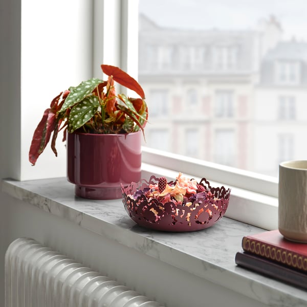 Small pink SILKESTRÄD steel bowl sits on a windowsill, surrounded by decorative items.