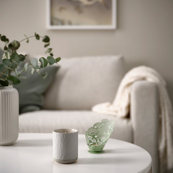 Cosy living room with light couch, throw blanket, candle holder, and greenery.