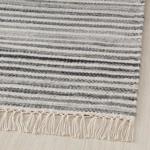 Modern hand-woven wool rug with grey stripes and soft fringes, displaying high quality craftsmanship.