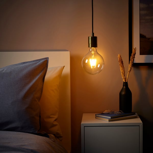 Cosy bedroom with SKAFTET pendant lamp over bedside table. Warm-toned, nickel-plated, energy-efficient design.
