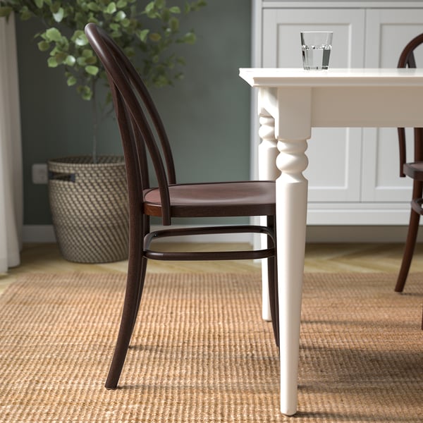 Wooden chair with curved back next to glass-topped table for dining.