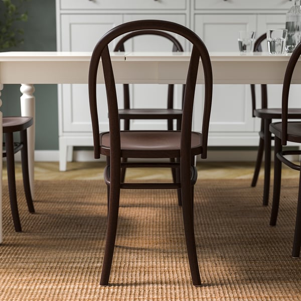 Wooden chair with curved back design, suitable for dining, in a room setting with table and cups.