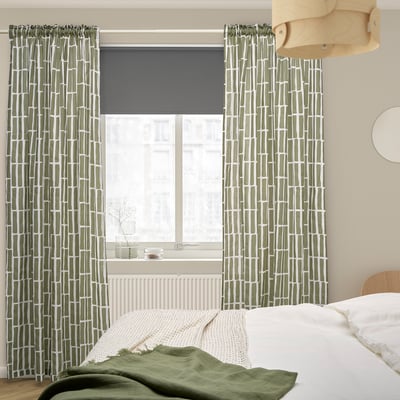 Green SKOGSSTJÄRNA curtains with geometric patterns in bedroom, covering large window.