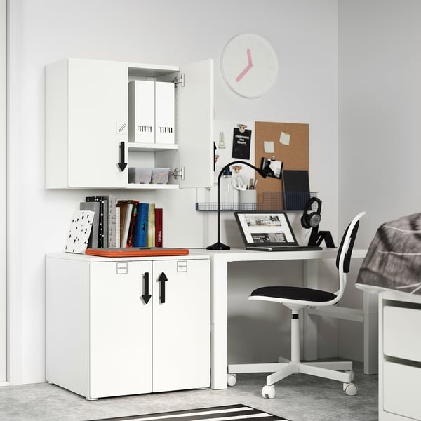Small white home office setup: white desk, chair, cabinet, books, laptop, headphones.