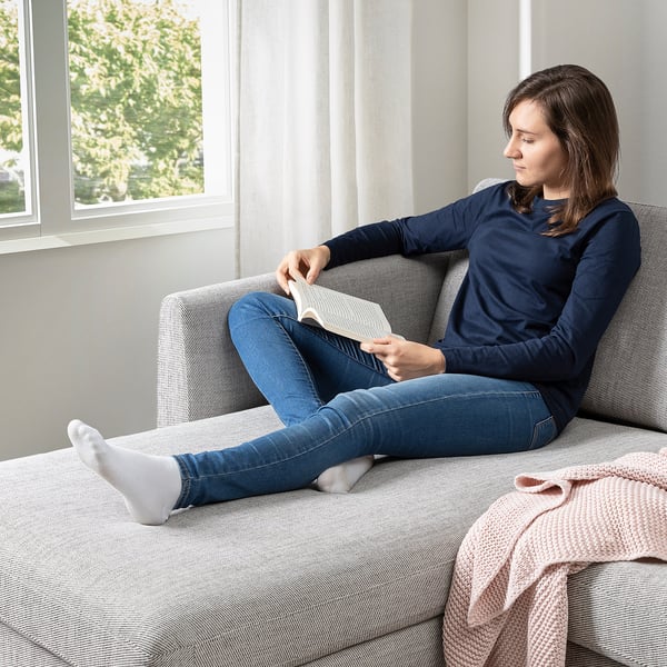 Person reading on soft, high-legged sofa by window, comfortable, likely SMEDSTORP.