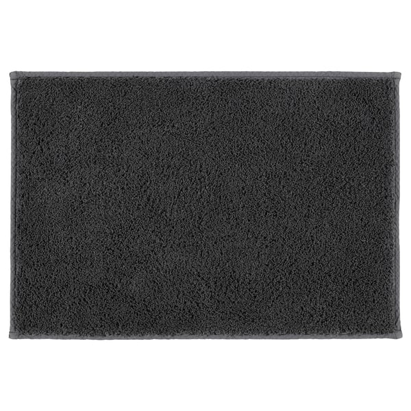 A dark grey SÖDERSJÖN bath mat. It has a rectangular shape with a plush cotton surface and latex backing for grip.