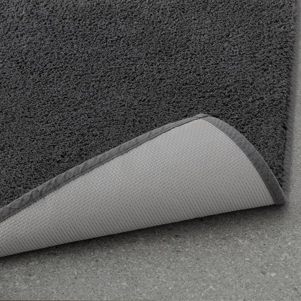 Soft grey bath mat with latex backing, thick cotton pile for comfort, folded to show texture.