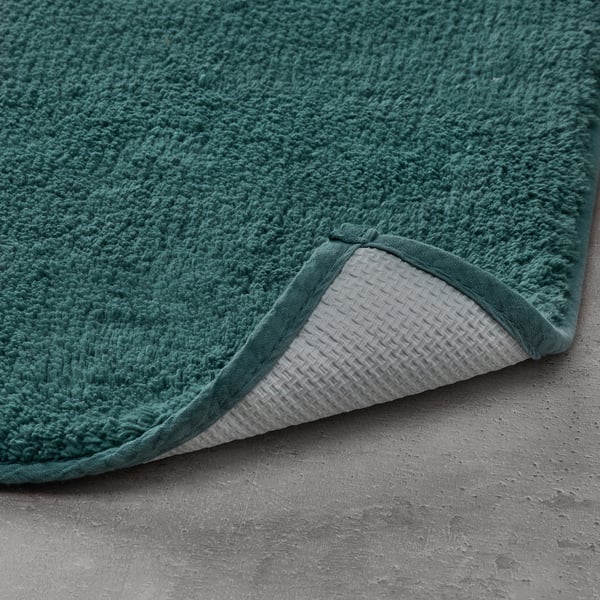 Dark green bath mat with white backing, boasting soft cotton texture, providing comfort and safety.