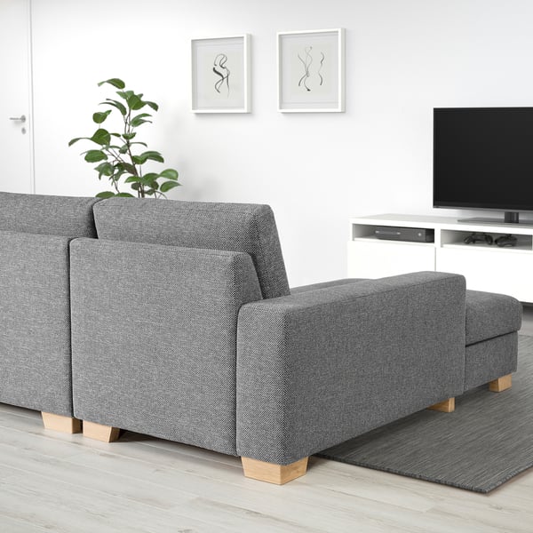 Modern grey sofa with chaise, minimalist style, light wooden legs, situated in a clean, bright living space.