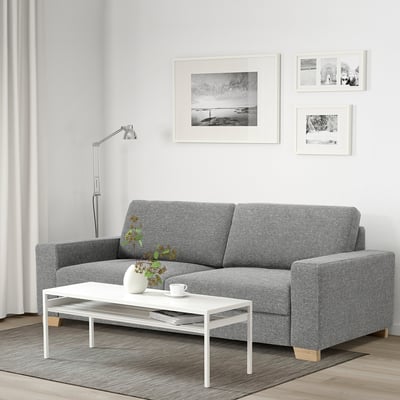 Minimalist living room with grey sofa, white table, wall art, lamp & photos.