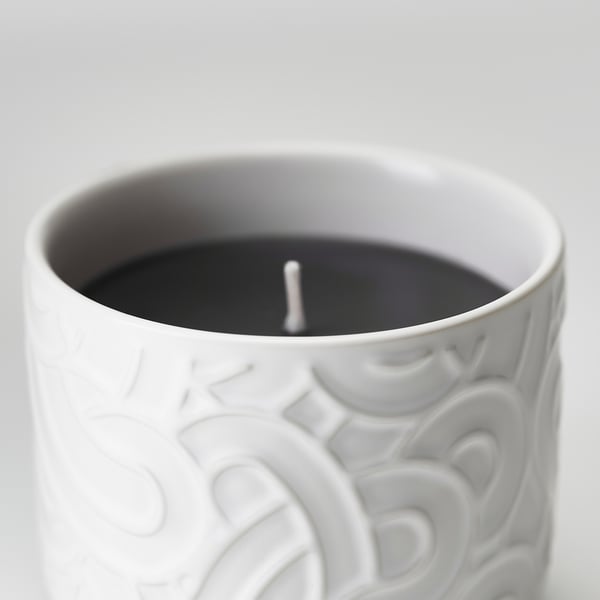 Close-up of white ceramaic candle holder with dark interior and textured swirls.