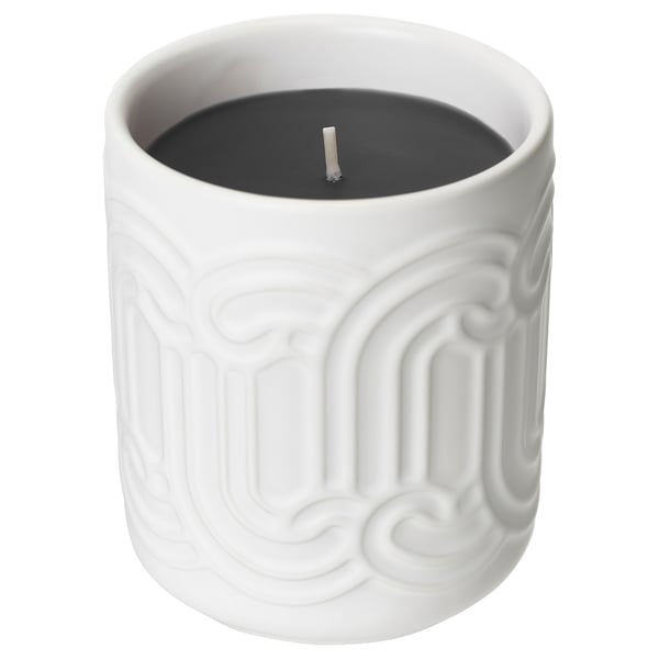 A white ceramic SÖTRÖNN candle with black wax a textured, curved design. It emits a vanilla-berry scent.