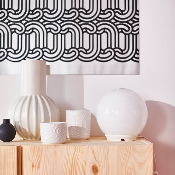 Wooden shelf with black/white wallpaper, vases, and a large white candle.