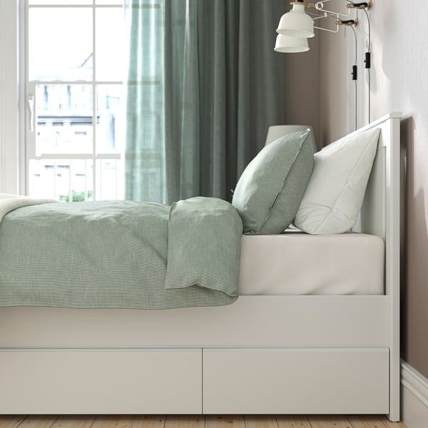 Modern bed frame with high legs and built-in storage drawers for bedding or clothes. Classic, sturdy design with adjustable bed sides.
