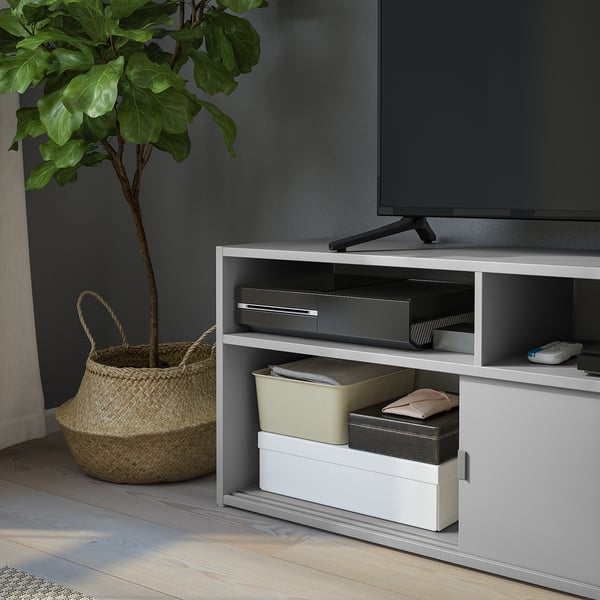 White tv stand with sliding doors and open storage, keeping electronics like a soundbar and cables organised and hidden.