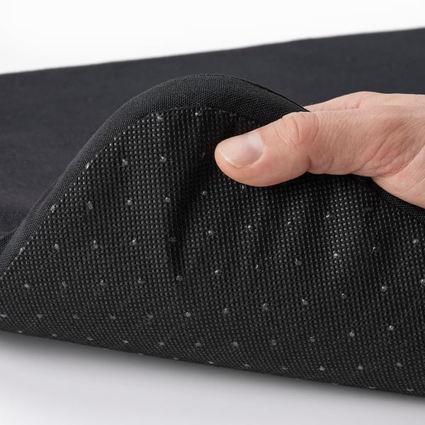 Hand pressing a black, textured STAGGSTARR chair pad, showcasing its removable cover for easy washing.