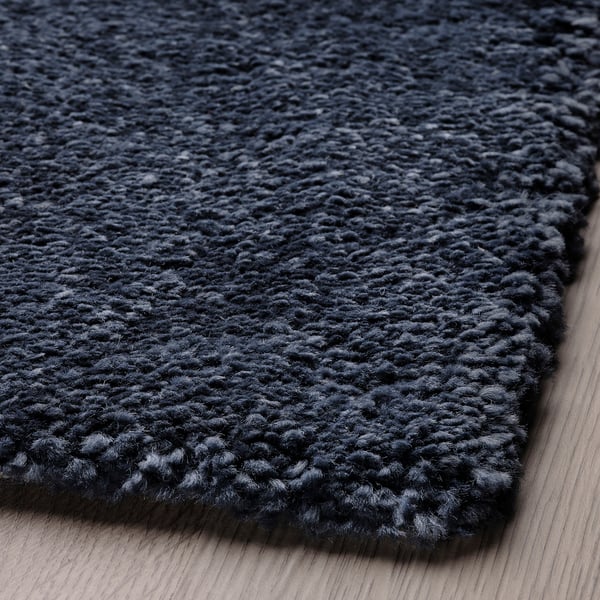 Soft, plush black rug laid on wooden floor, showcasing its thick, high-quality pile.