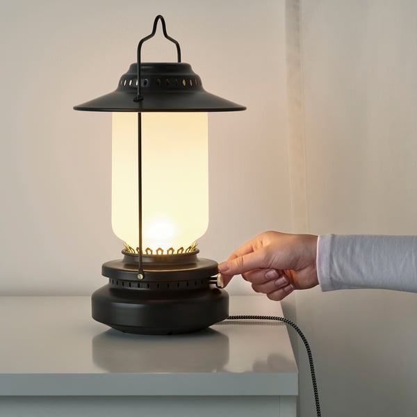 A hand adjusts a dimmable STORHAGA lamp, suitable for indoor/outdoor use, on a light table.