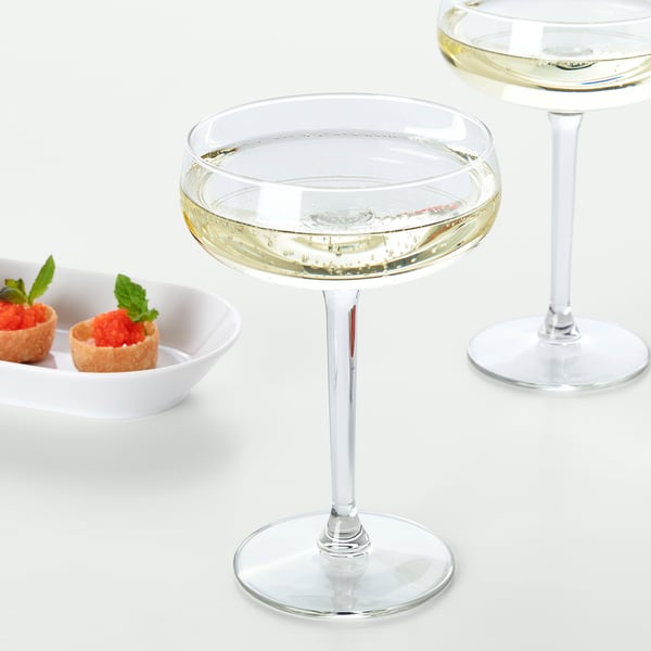 Two wine glasses filled with sparkling wine, accompanied by a small dish of dessert cups garnished with mint leaves.