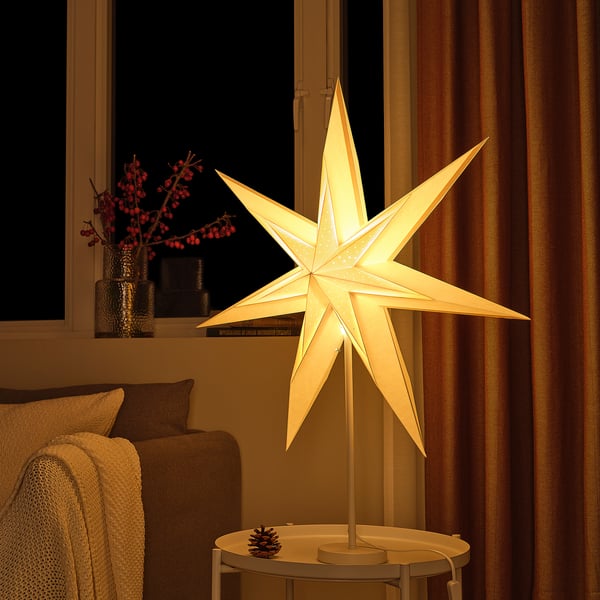 Cosy illuminated star lamp in living room, resting on small table beside couch.