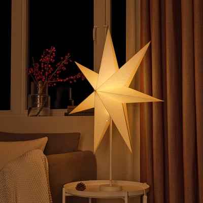 Cosy star lamp with linen shade and pine cone decor.