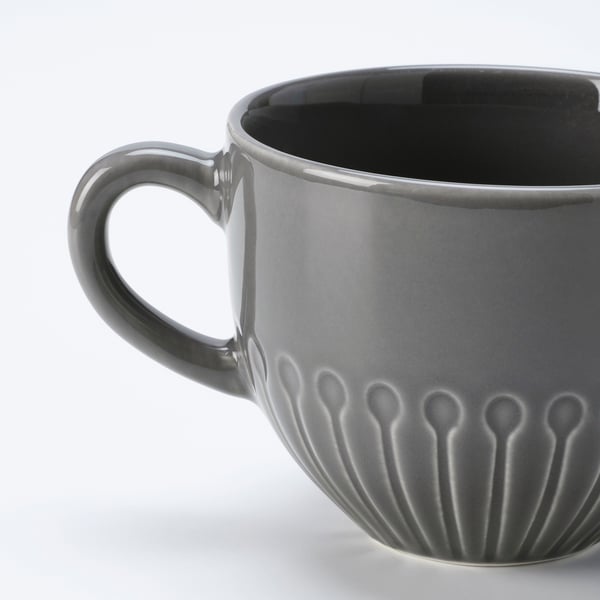 Dark grey ceramic mug with a smooth handle and textured flower pattern near the base. Glazed finish, designed with a modern, clean look.