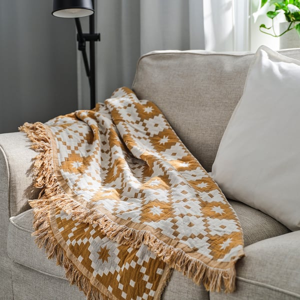 Geometric throw blanket with fringe on grey couch.