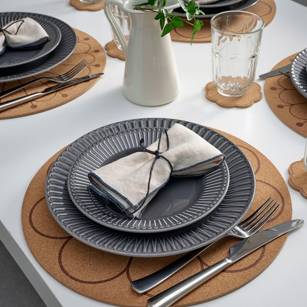 Elegant table setting with SVARTVIDE place mats and plates, featuring shibori-inspired design, protecting table and reducing noise.