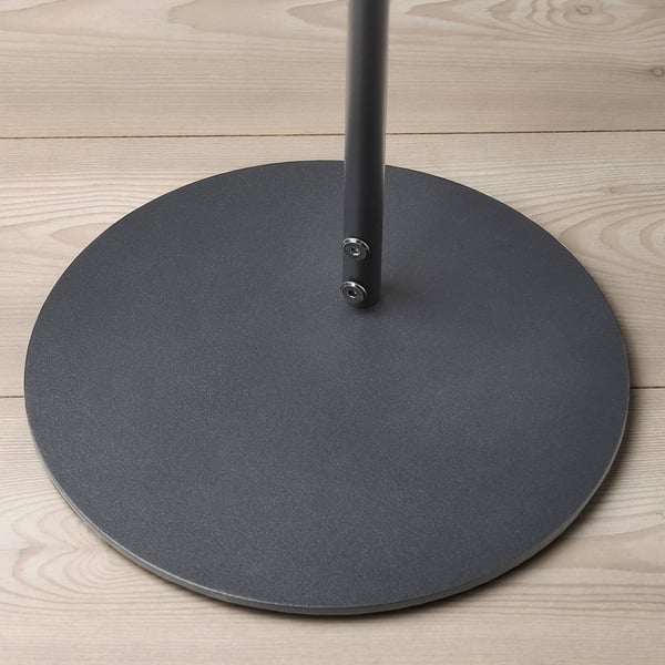 Circular grey metal speaker stand on light wood floor.