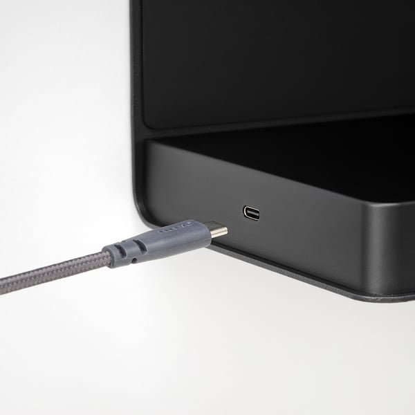A sleek black device with a usb-c port connected to a braided grey cable, indicating wireless charging functionality.