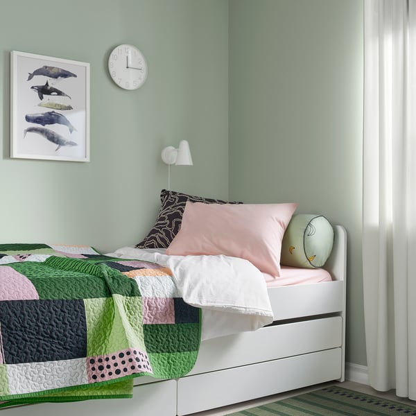 Colourful patchwork bedspread on twin bed, light green walls, dolphin art, pink & owl pillows, minimalist design.