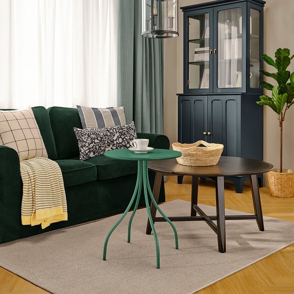 Modern living room with dark green TÅNEBRO side table, glass coffee table, emerald sofa, black cabinet, and wooden floor.