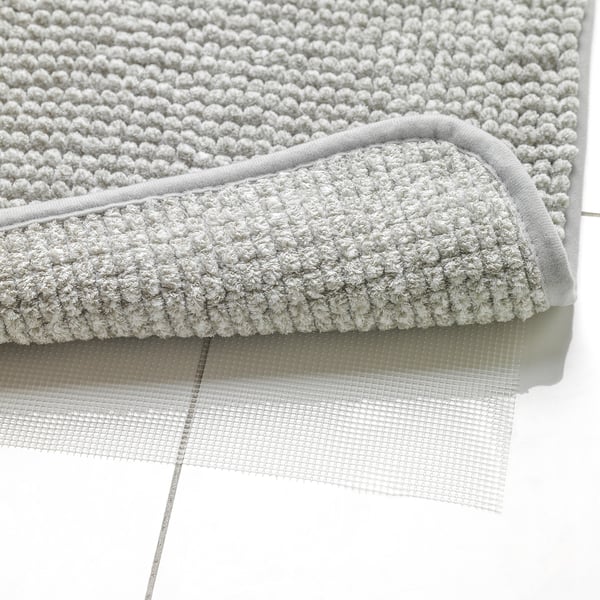 Folded grey bath mat with non-slip mesh layer underneath. Textured for absorption, quick drying.