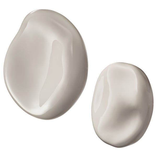 Two smooth, rounded, white ceramic wall hangings with glossy finish. One larger, one smaller, both organic-shaped.