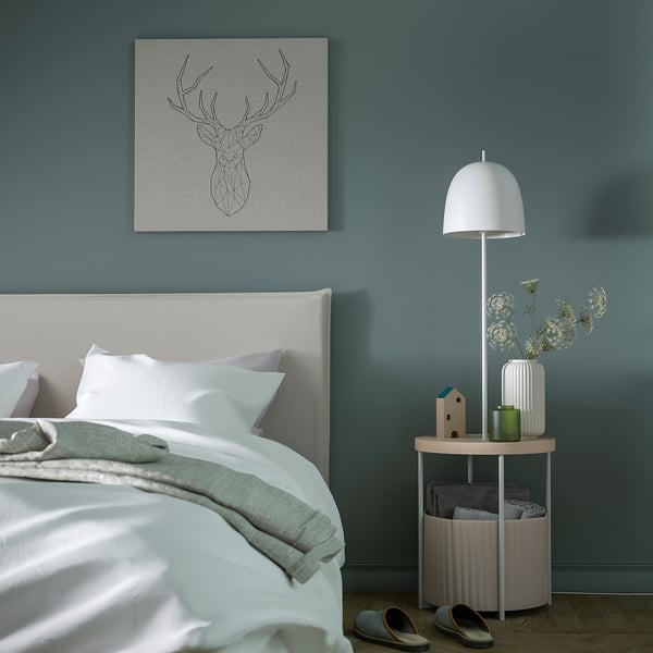 Minimalist bedroom with TRINDSNÖ unit. White lamp, side table, storage basket. Blue-green walls, pastel accents.