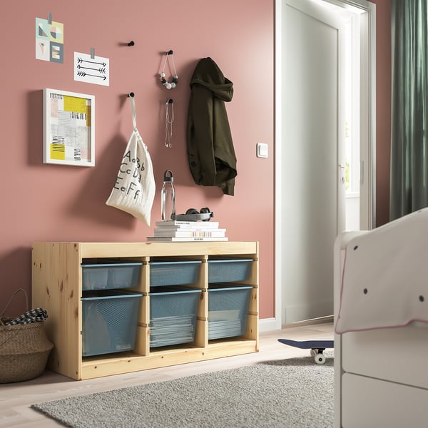 TROFAST storage unit with mesh boxes in pink room, holding books, glasses, coat.