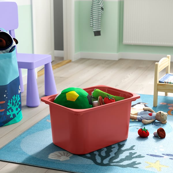 Red TROFAST bin on rug with colourful toys.