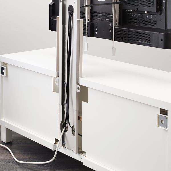 White tv bracket mounted on wall holding flat screen, with cables neatly organised behind it.
