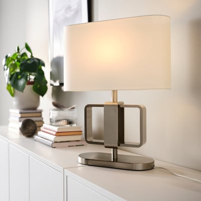 Modish UPPVIND lamp, sleek gold metal, oval shade. Its small, fits neatly on a desk with books & plants.