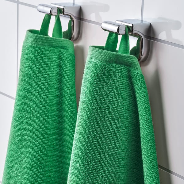 Two bright green towels hang on silver hooks, showcasing their absorbent, fast-drying texture and vivid colour.