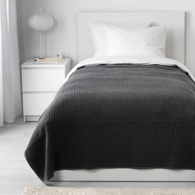 VÅRELD grey cotton bedspread covers a white single bed, larger than bedside drawers.