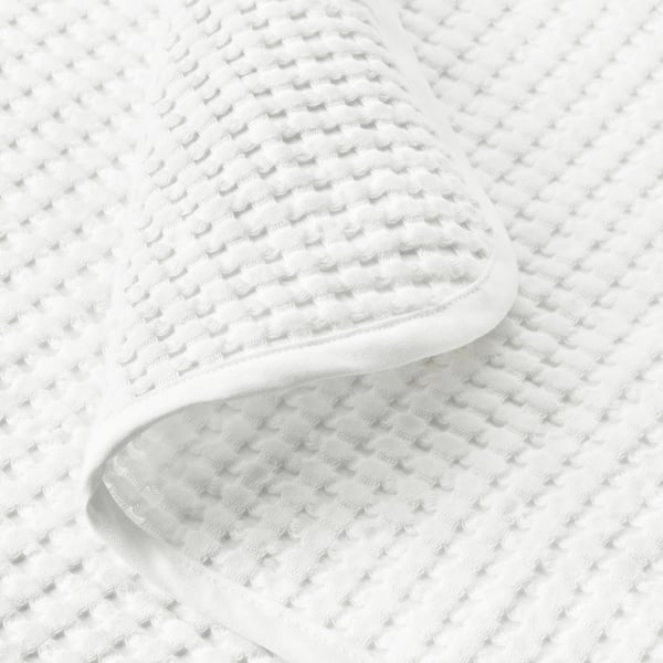 Close-up of soft, textured white cotton bedspread; comfortable and cosy weave.