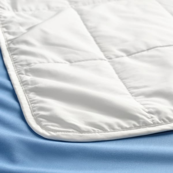 Close-up of a smooth, white duvet with delicate stitching, laid on a light blue sheet.