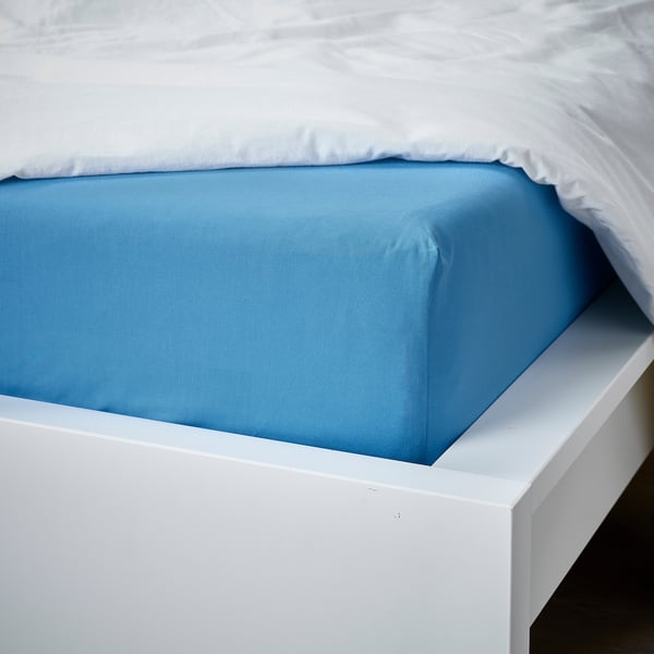 Blue fitted sheet on white bed, covering mattress corner.