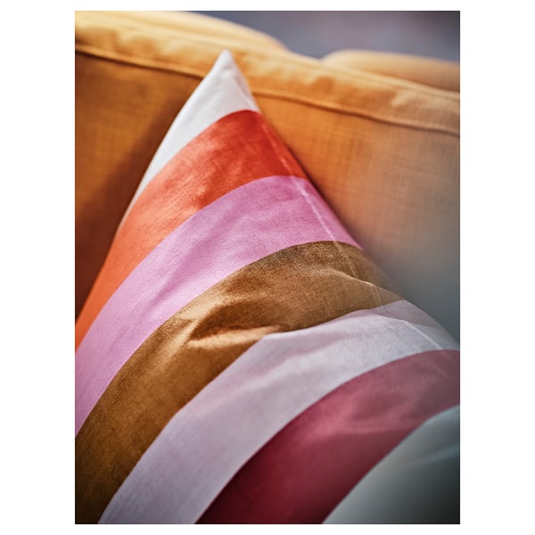 VATTENVÄN cushion, orange-pink bands, soft texture, folded on couch. Small square.
