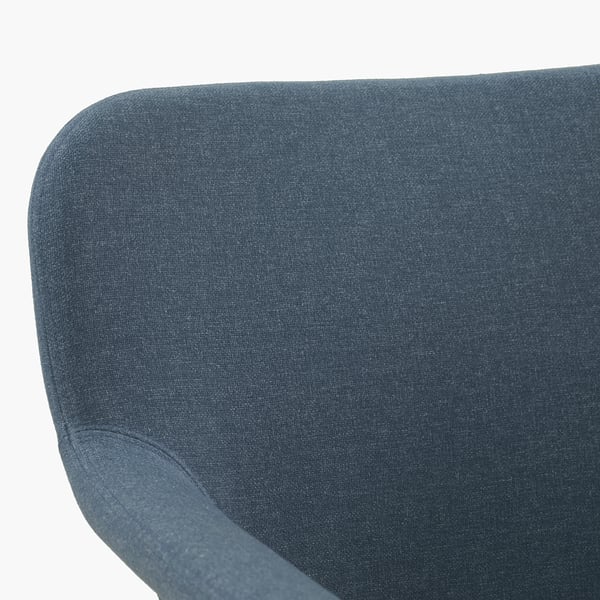 Dark blue upholstered chair close-up. Soft, curved lines, quality fabric.