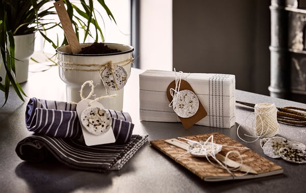 Table display with white VERKLIGHET folded napkins, striped blue napkins, and decorative gift tags, in a cosy rustic design.