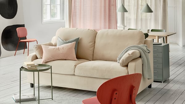 Beige sofa with pink pillows, glass table, red chair, wood floor